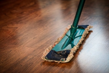 Dust mop cleaning laminate wood floor.